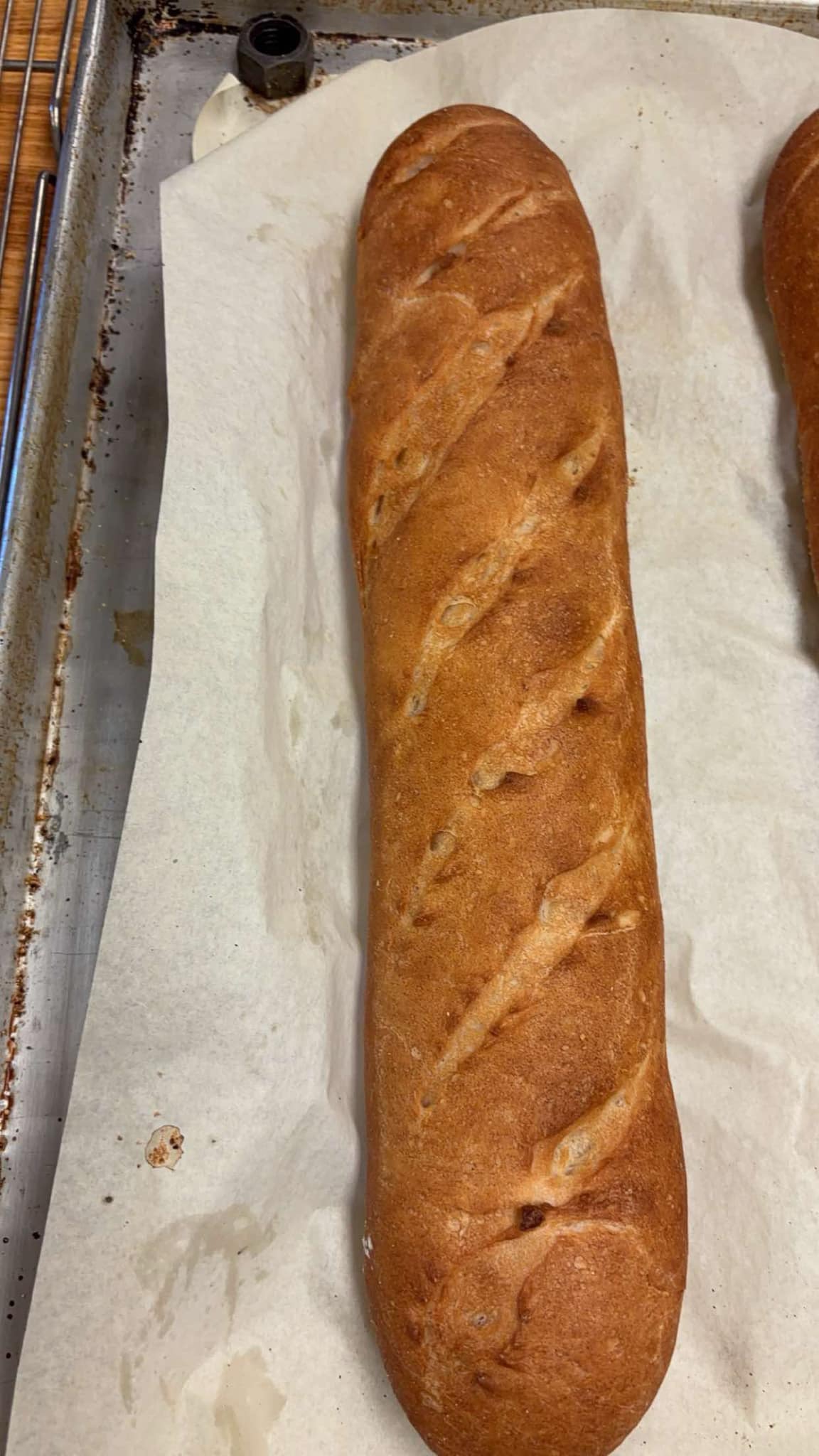 Crusty French baguette, sharply scored, on parchment