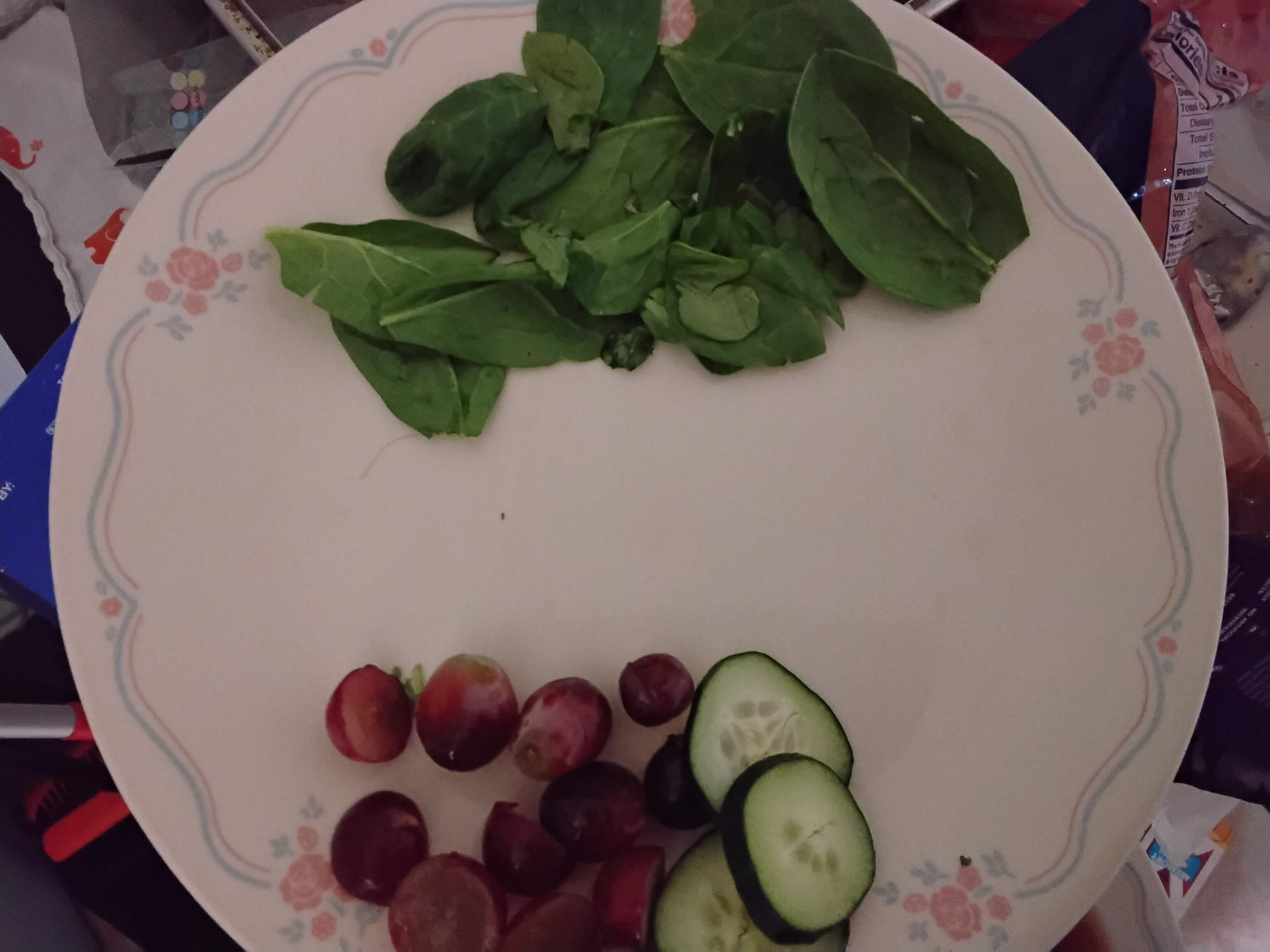 Plate with red grapes, sliced cucumber and fresh baby spinach, mise en place